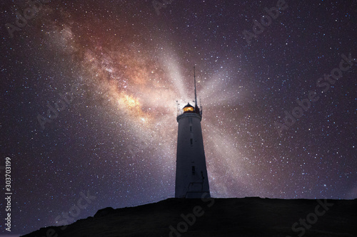 lighthouse shines bright in a night sky of stars