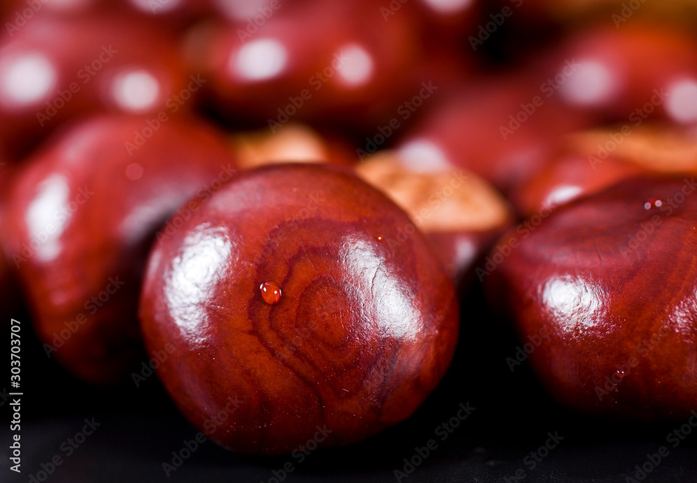 Obraz premium Drop of water on a textured chestnut. Macro. Selective focus.