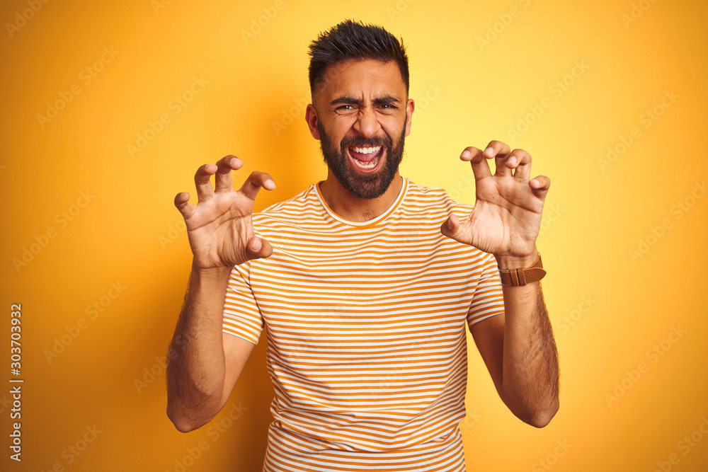 Young indian man wearing t-shirt standing over isolated yellow background  smiling funny doing claw gesture as cat, aggressive and sexy expression  Stock Photo | Adobe Stock