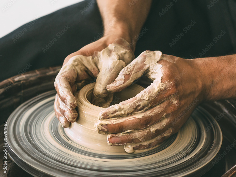 Ceramist at a pottery workshop A man is working behind a potter's wheel Close-up photo - obrazy, fototapety, plakaty 