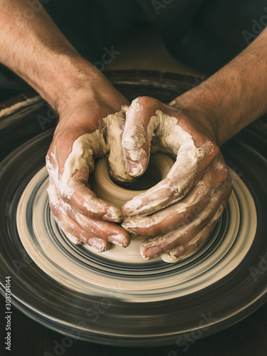 Ceramist at a pottery workshop A man is working behind a potter's wheel Close-up photo