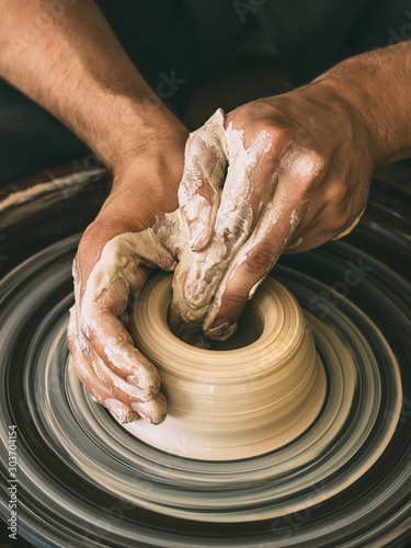 Ceramist at a pottery workshop A man is working behind a potter's wheel Close-up photo