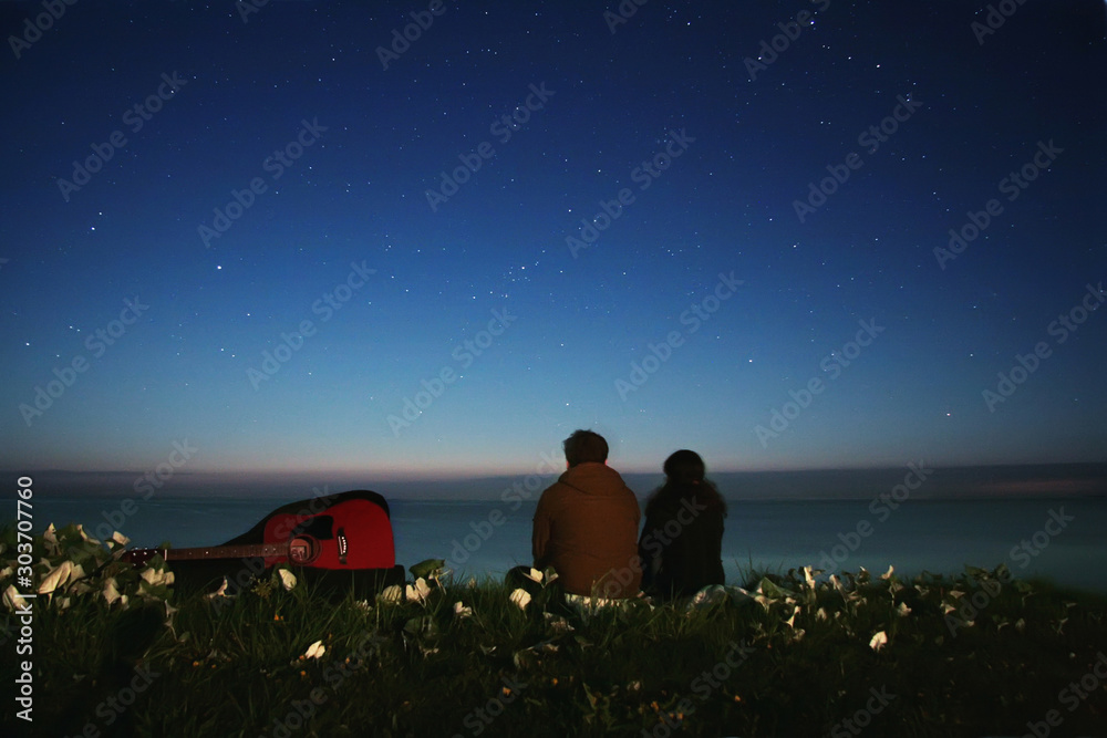 couple with a guitar on the beach under the stars