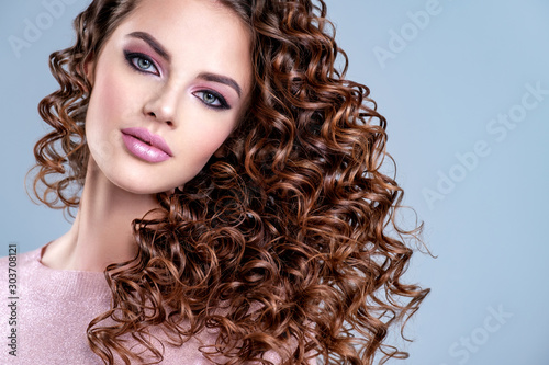  Young girl with wavy hair. Portrait of a beautiful woman with a long hair. Young  model with beautiful curly hair - isolated on white background. Young woman with bright eye make-up, long eye lashes