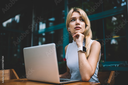 Thoughtful freelancer with laptop looking away