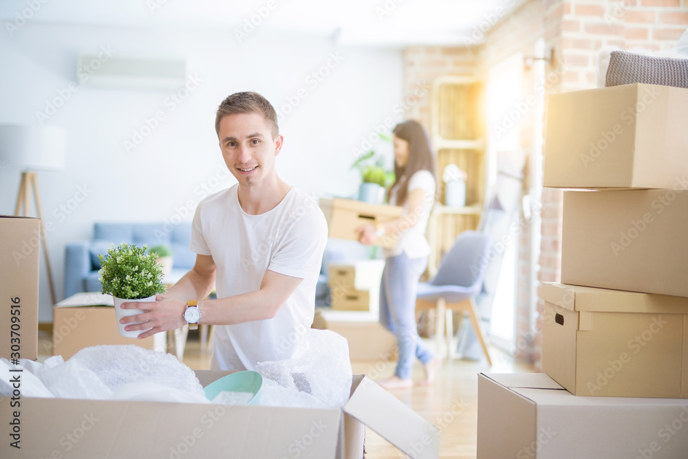 Young beautiful couple open cardboard boxes to order new home Young beautiful couple open cardboard boxes to order new home