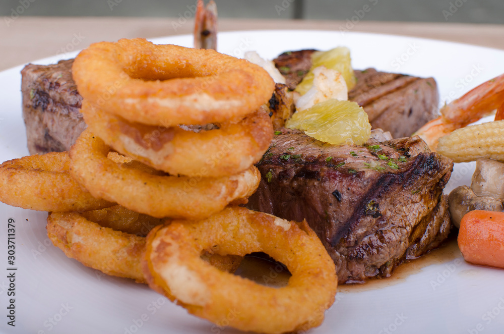 Grilled meat accompanied by onion rings and salad