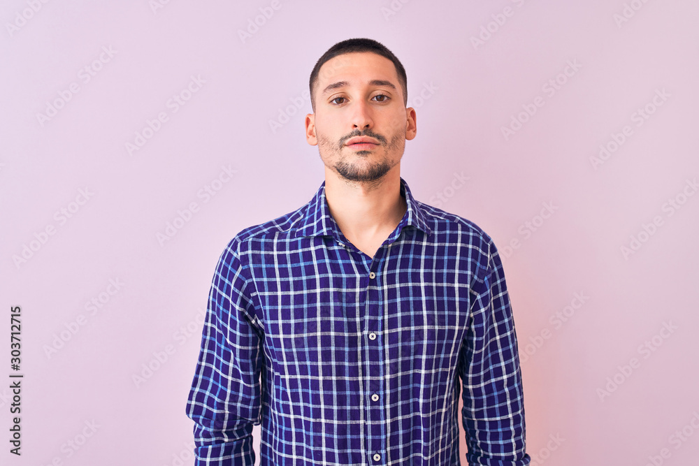 Young handsome man standing over isolated background Relaxed with serious expression on face. Simple and natural looking at the camera. Young handsome man standing over isolated background Relaxed with serious expression on face. Simple and natural looking at the camera.