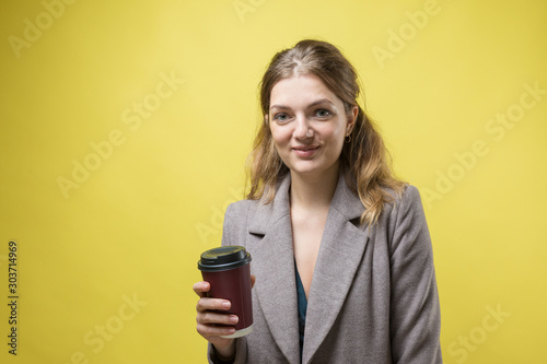 Glamor woman with a drink of coffee on a yellow background 