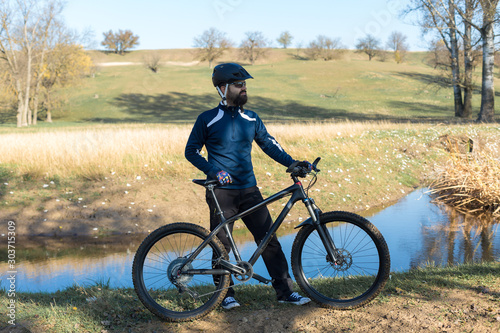 Cyclist in pants and fleece jacket on a modern carbon hardtail bike with an air suspension fork rides off-road. 