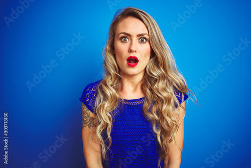 Young beautiful woman standing over blue isolated background afraid and shocked with surprise expression, fear and excited face.