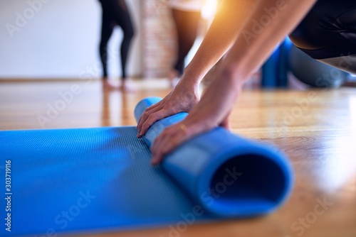Young beautiful sportwoman using sport mat to practice yoga at gym