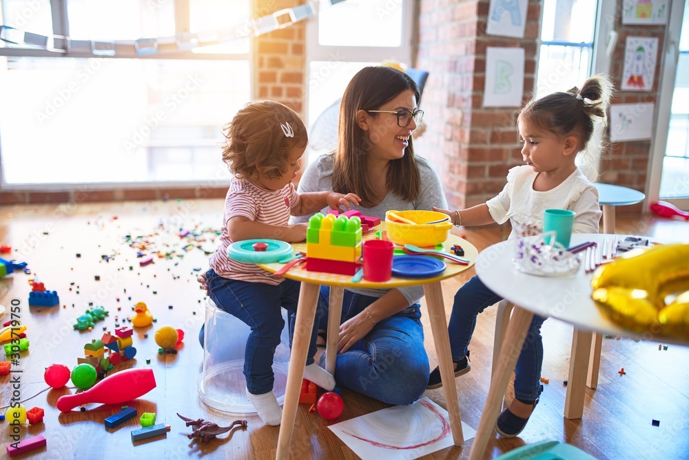 Φωτογραφία Young beautiful teacher and toddlers playing on the table with lots of toys at k