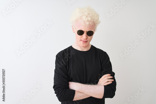 Young albino man wearing black t-shirt and sunglasess standing over isolated white background skeptic and nervous, disapproving expression on face with crossed arms. Negative person. photo