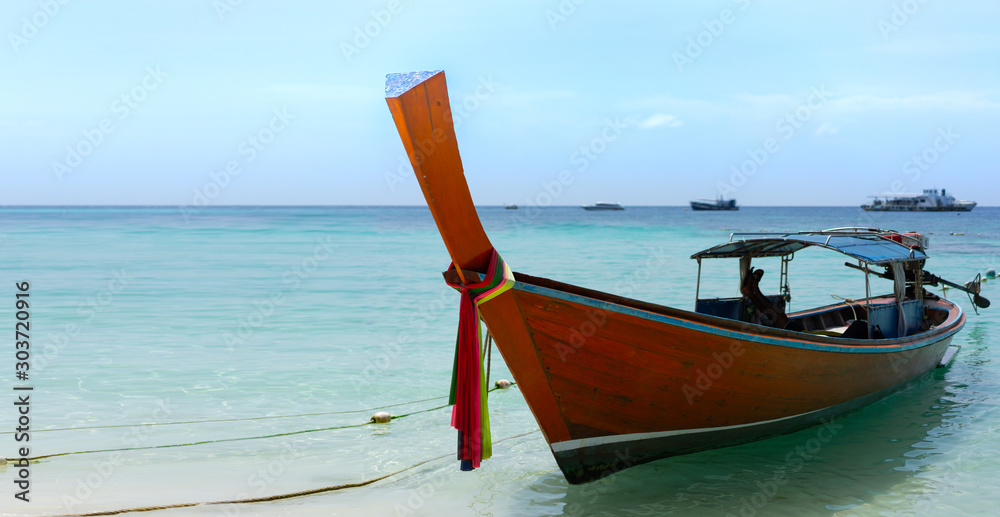 Thai traditional longtail boats parked on a white sand beach surrounded by crystal clear turquoise water on a sunny, blue sky day on Thai paradise island of Ko Lipe, Thailand. Horizontal copy space Thai traditional longtail boats parked on a white sand beach surrounded by crystal clear turquoise water on a sunny, blue sky day on Thai paradise island of Ko Lipe, Thailand. Horizontal copy space