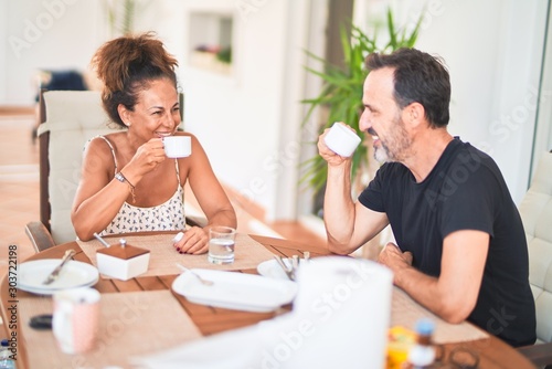 Middle age beautiful couple sitting on terrace drinking cup of coffe