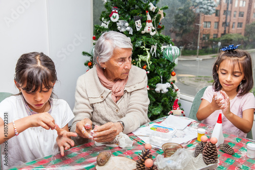 Little girls having fun while making christmas Nativity crafts with their grandmother - Real family