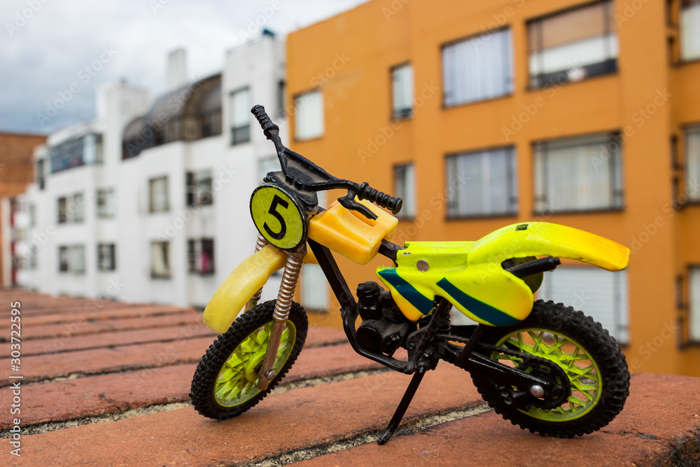 Mini Motocross Bike Toy green and yellow with building Background