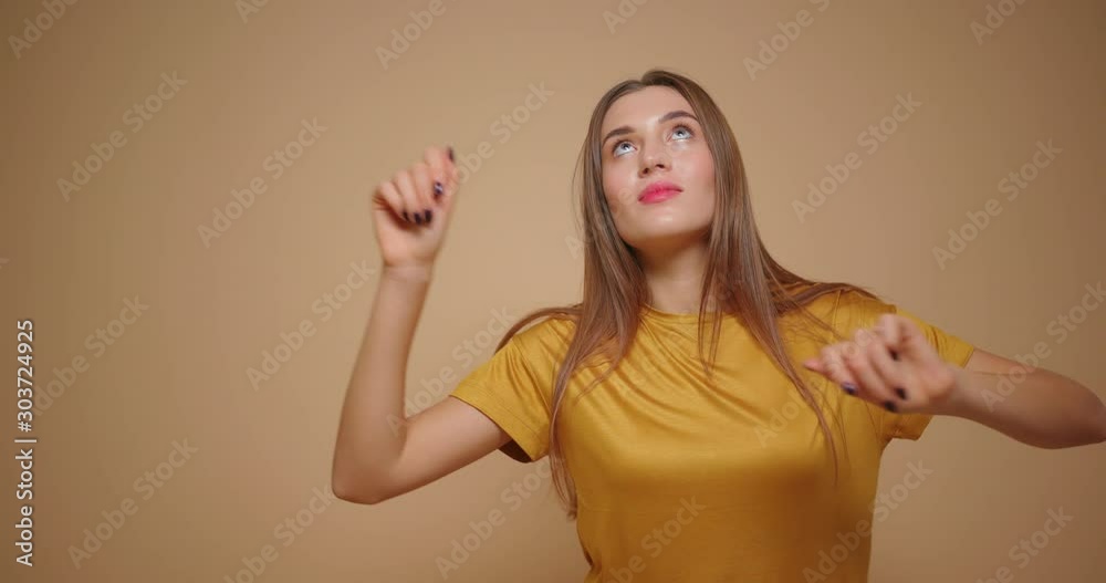Brunette woman in yellow t shirt happy dancing isolated on beige background. Brunette woman in yellow t shirt happy dancing isolated on beige background.