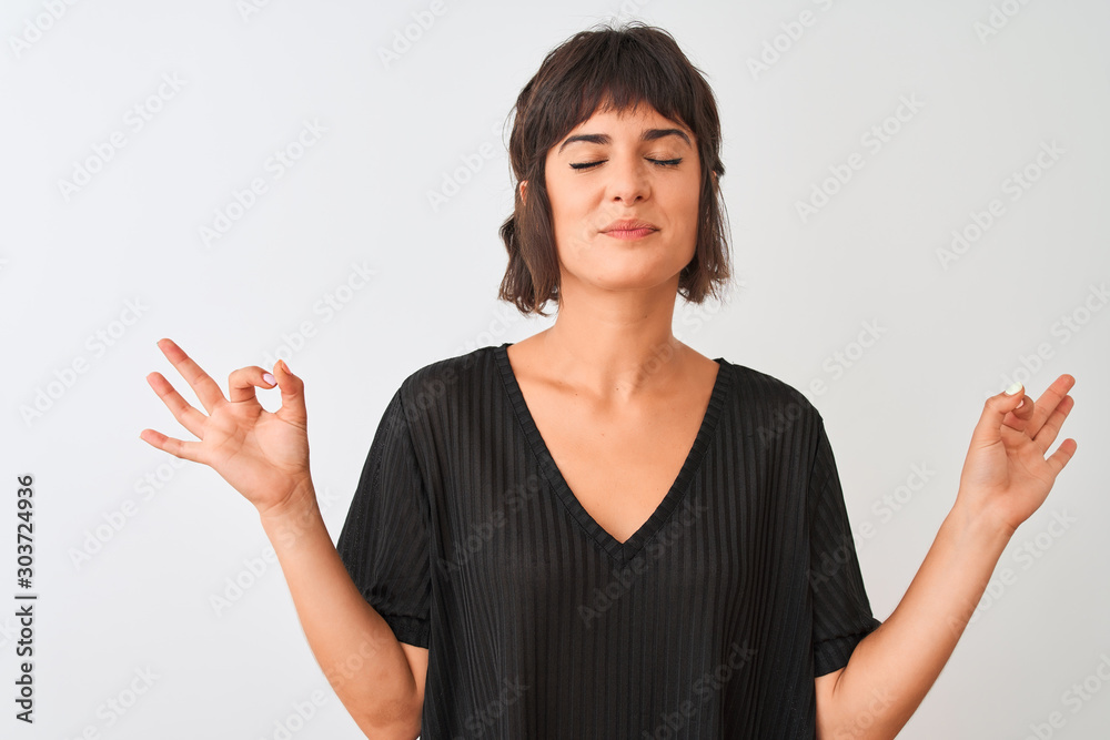 Young beautiful woman wearing black t-shirt standing over isolated white background relax and smiling with eyes closed doing meditation gesture with fingers. Yoga concept. Young beautiful woman wearing black t-shirt standing over isolated white background relax and smiling with eyes closed doing meditation gesture with fingers. Yoga concept.