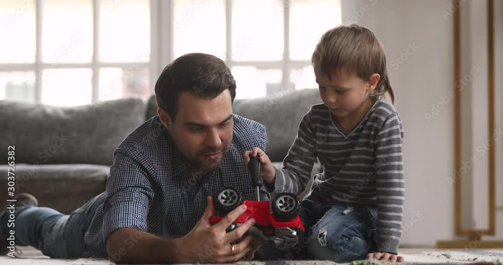 Daddy teaching cute kid son playing toy car on floor Daddy teaching cute kid son playing toy car on floor