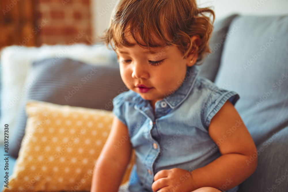 Beautiful toddler child girl wearing blue denim shirt sitting on the sofa Beautiful toddler child girl wearing blue denim shirt sitting on the sofa