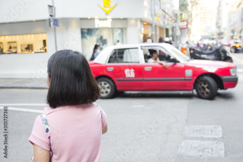 Wall Mural Young woman walking in Hongkong street with taxi cab in background