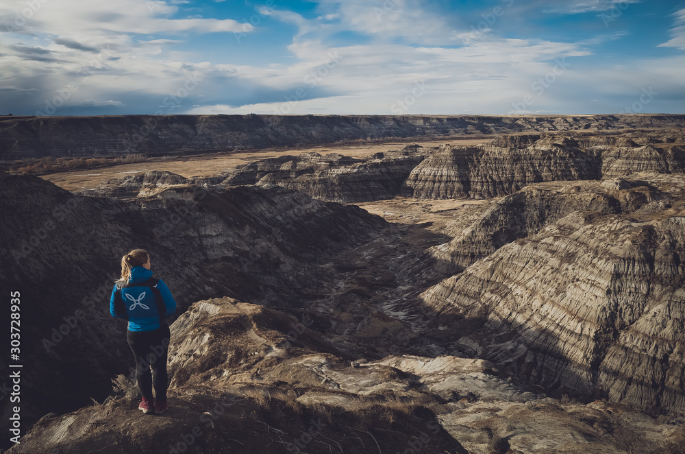 Young blonde woman hiked to Horsethief Canyon lookout to admire nature beauty of UNESCO heritage site, Drumheller, Alberta, Canada