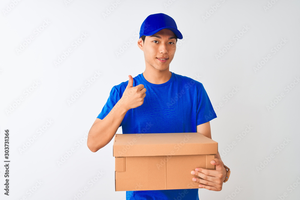Chinese deliveryman wearing cap holding box standing over isolated white background happy with big smile doing ok sign, thumb up with fingers, excellent sign Chinese deliveryman wearing cap holding box standing over isolated white background happy with big smile doing ok sign, thumb up with fingers, excellent sign