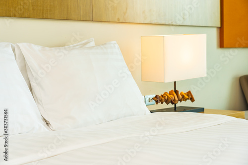White comfortable pillow on bed decoration with light lamp