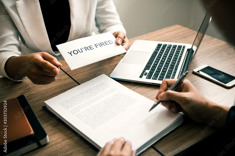 Female manager handed out the dismissal certificate to the male employee while signing the contract to quit from or resign. Female manager handed out the dismissal certificate to the male employee while signing the contract to quit from or resign.