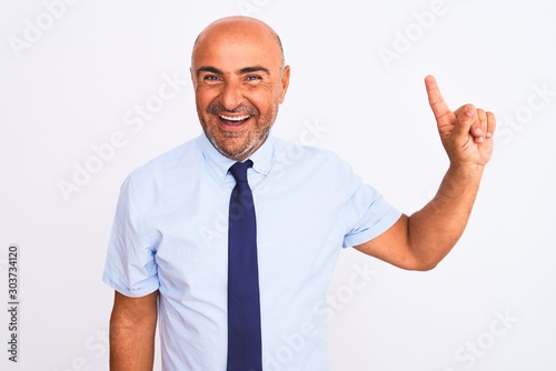 Middle age businessman wearing tie standing over isolated white background showing and pointing up with finger number one while smiling confident and happy.