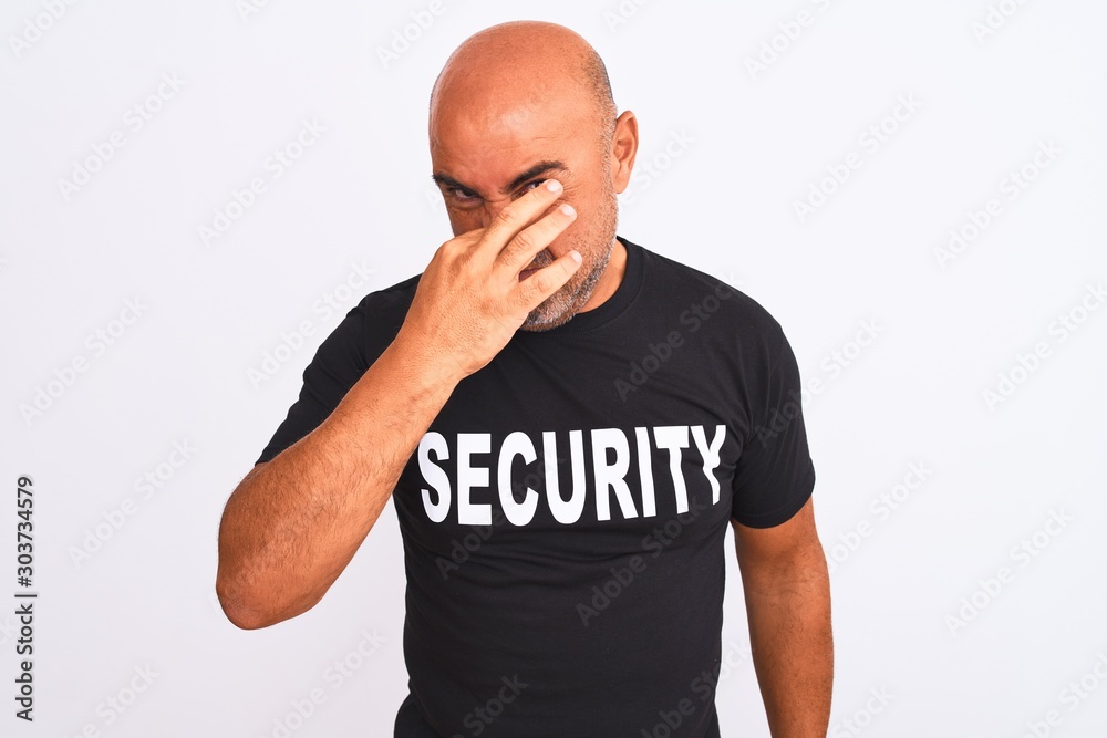 Middle age safeguard man wearing security uniform standing over isolated white background smelling something stinky and disgusting, intolerable smell, holding breath with fingers on nose. Bad smells Middle age safeguard man wearing security uniform standing over isolated white background smelling something stinky and disgusting, intolerable smell, holding breath with fingers on nose. Bad smells