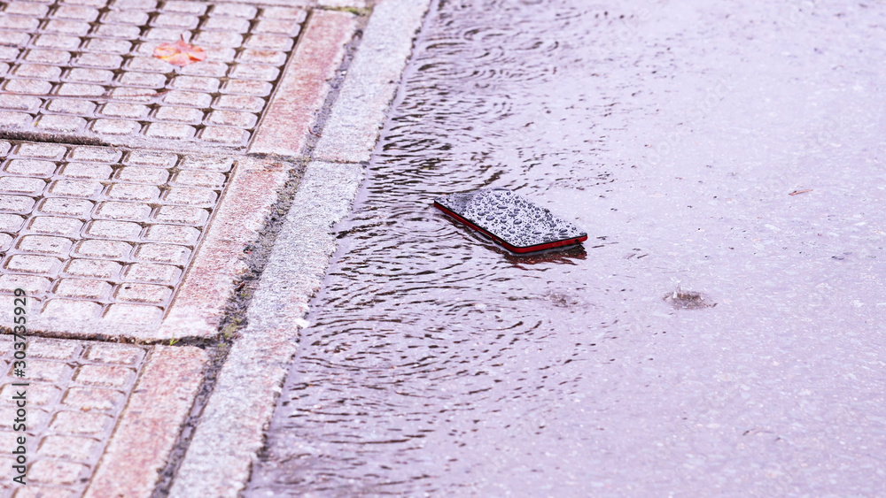 Φωτογραφία 雨の日の道路に落ちたスマートフォン