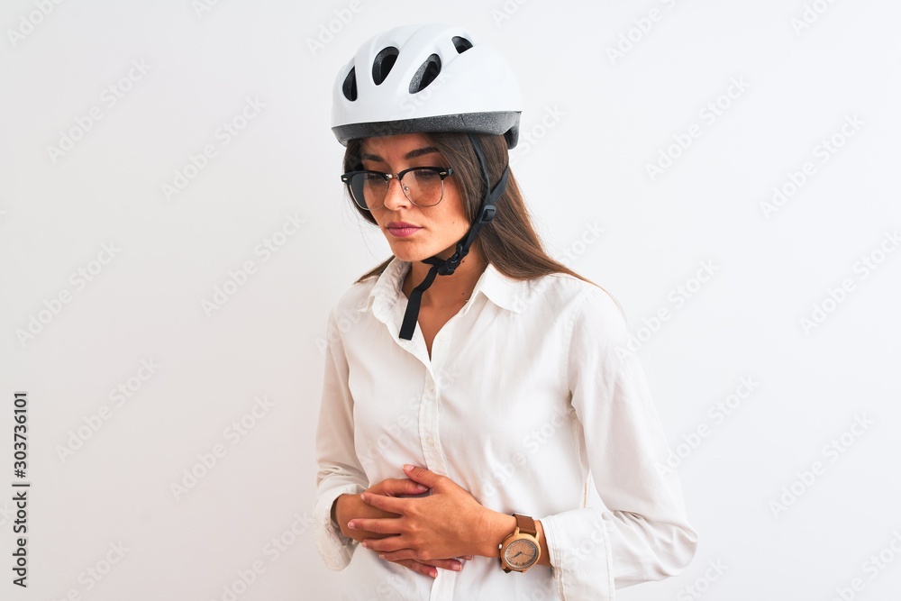 Beautiful businesswoman wearing glasses and bike helmet over isolated white background with hand on stomach because nausea, painful disease feeling unwell. Ache concept. Beautiful businesswoman wearing glasses and bike helmet over isolated white background with hand on stomach because nausea, painful disease feeling unwell. Ache concept.