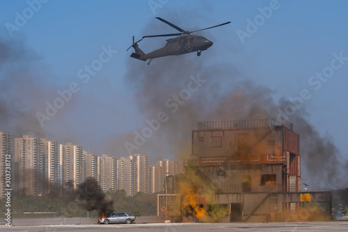 American Black Hawk helicopter Sikorsky UH - 60M attack takes off at the operation the rescue mission between smoke in battle war on the blue sky. Concept the insurgency in the capital photo