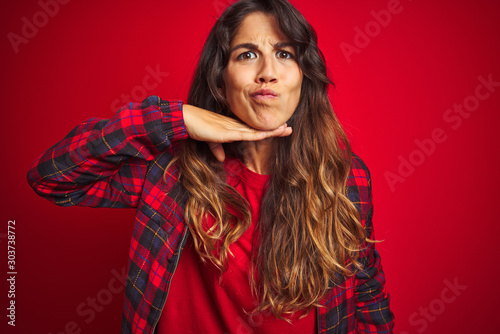 Young beautiful woman wearing casual jacket standing over red isolated background Beckoning come here gesture with hand inviting welcoming happy and smiling