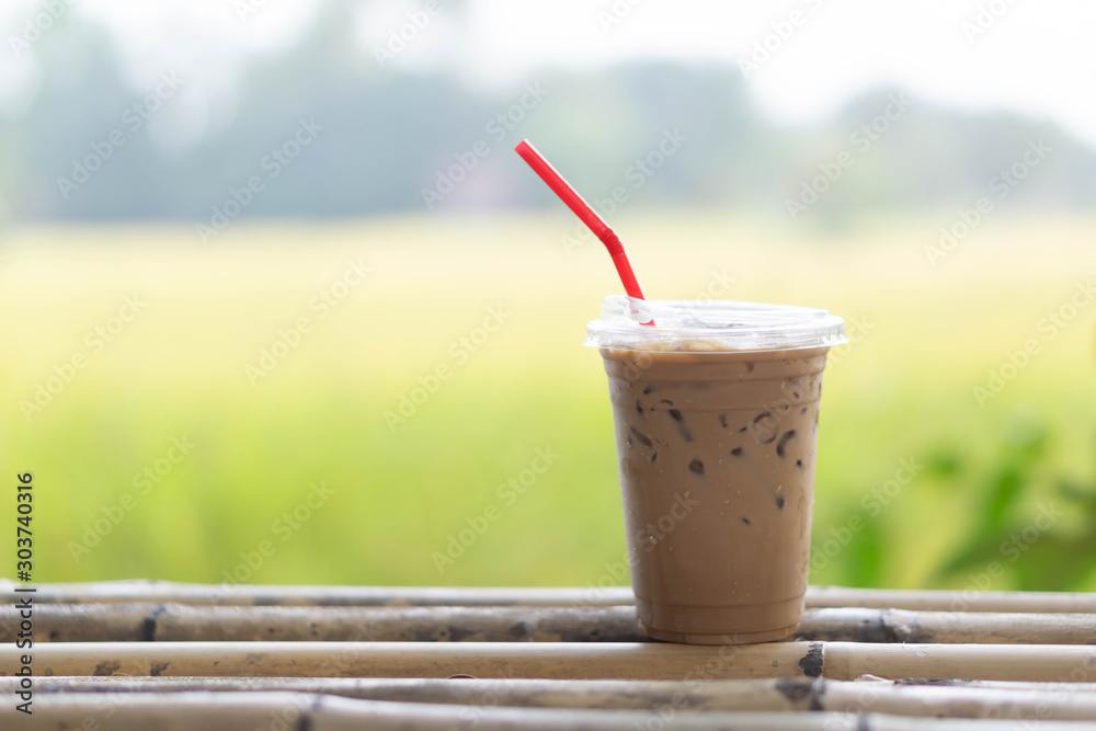 Close up glass of ice cappuccino coffee on wood table with green nature background, selective focus Close up glass of ice cappuccino coffee on wood table with green nature background, selective focus