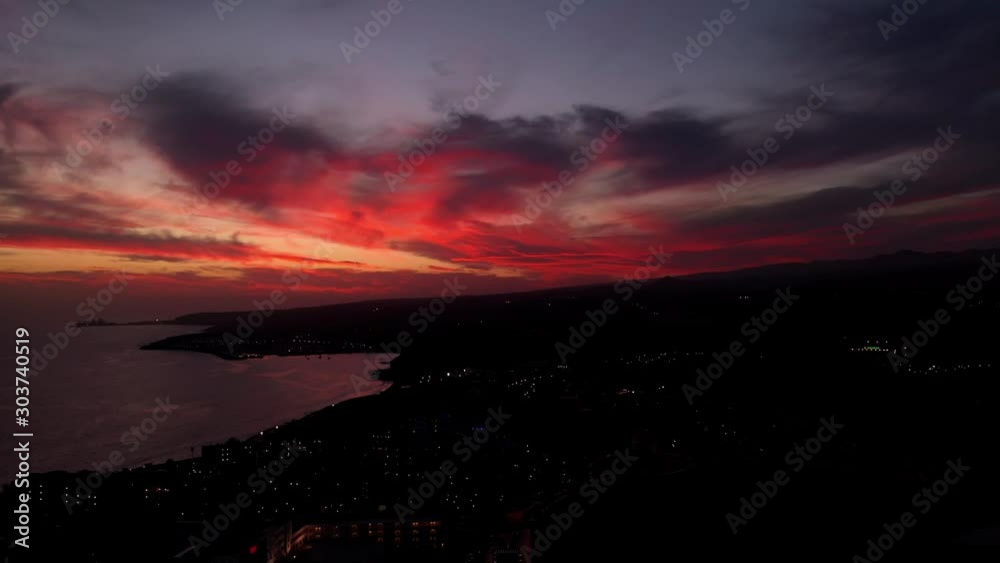 tilt and move Las Palmas Gran Canaria at nightfall with vibrant red clouds, aerial drone at sea tilt and move Las Palmas Gran Canaria at nightfall with vibrant red clouds, aerial drone at sea