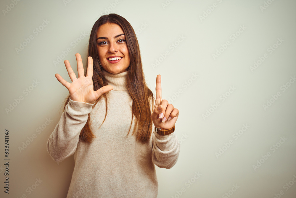 Young beautiful woman wearing winter turtleneck sweater over isolated white background showing and pointing up with fingers number six while smiling confident and happy. Young beautiful woman wearing winter turtleneck sweater over isolated white background showing and pointing up with fingers number six while smiling confident and happy.