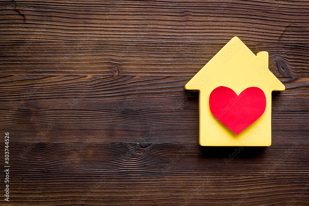 Happy life and home concept. House cutout and heart icon on dark wooden background top view space for text Happy life and home concept. House cutout and heart icon on dark wooden background top view space for text