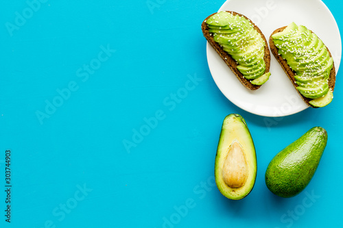 Healthy food. Avocado toast on blue background top view frame copy space