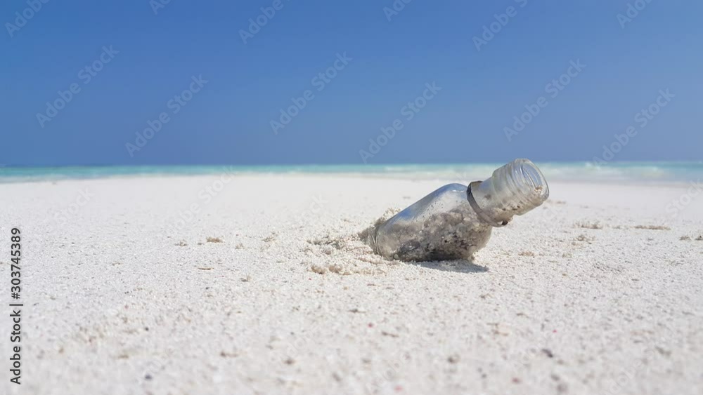 Plastic bottle leftover on white sand of polluted beach contaminating environment where many sea species are in danger Plastic bottle leftover on white sand of polluted beach contaminating environment where many sea species are in danger