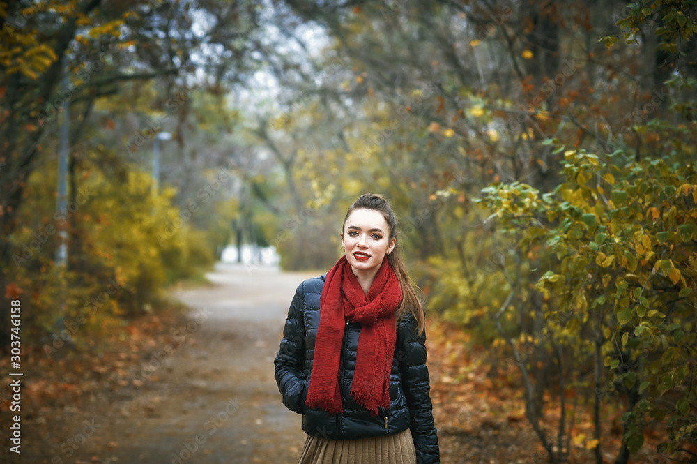 Portrait of a young beautiful woman in the autumn Park . The girl in the red scarf Portrait of a young beautiful woman in the autumn Park . The girl in the red scarf