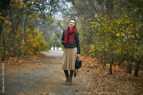 Portrait of a young beautiful woman in the autumn Park . The girl in the red scarf