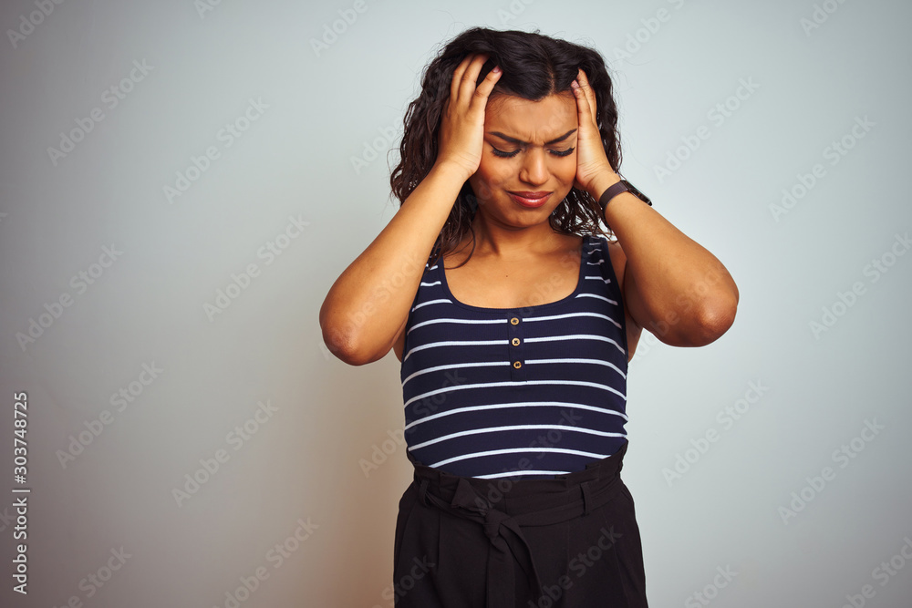 Transsexual transgender woman wearing striped t-shirt over isolated white background suffering from headache desperate and stressed because pain and migraine. Hands on head. Transsexual transgender woman wearing striped t-shirt over isolated white background suffering from headache desperate and stressed because pain and migraine. Hands on head.