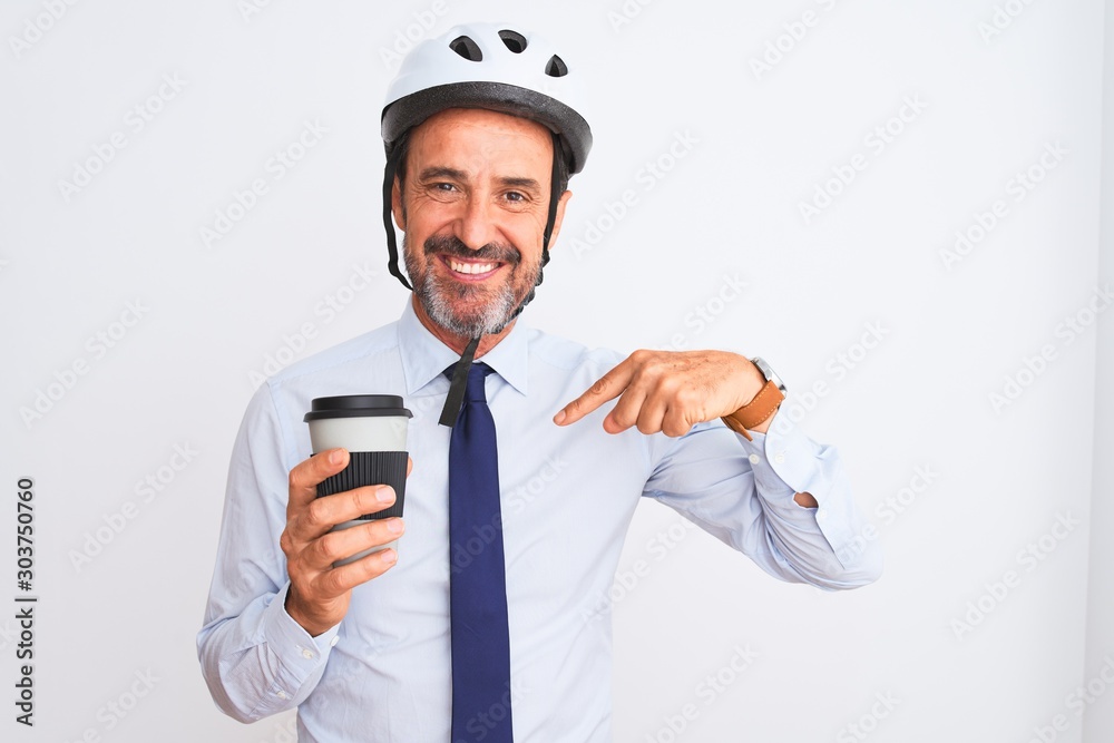 Middle age businessman wearing bike helmet drinking coffee over isolated white background with surprise face pointing finger to himself