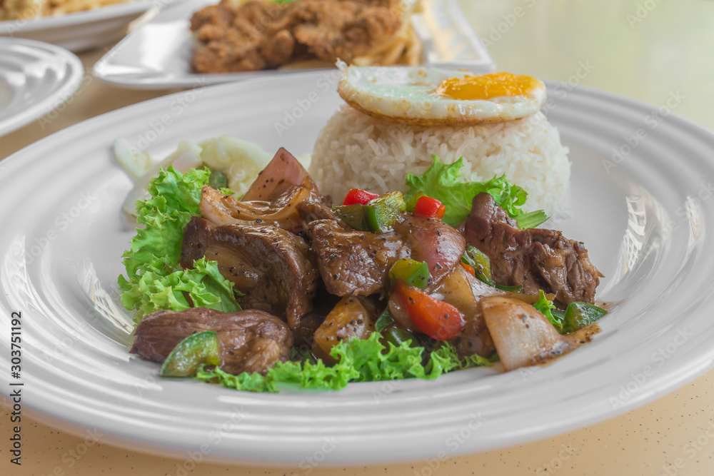 Asian Chinese Stir-fried spicy pepper beef with lettuce, jasmine white rice, pickled vegetables and sunny-side up fried egg