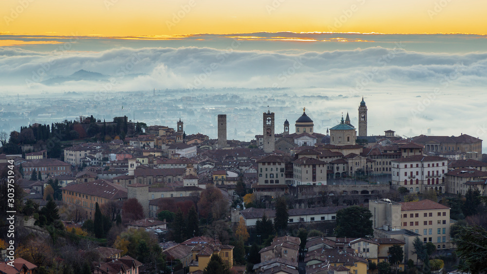 Bergamo, Italy. Amazing landscape of the town covered by the fog arising from the plain. Fall season. Morning. Sunrise time