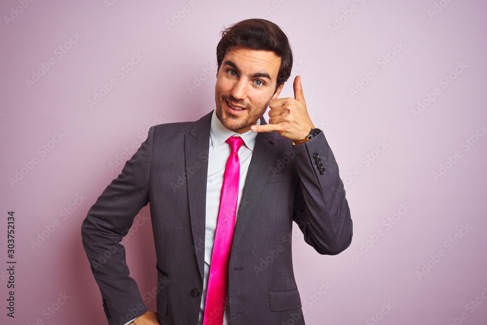 Φωτογραφία Young handsome businessman wearing suit and tie standing over isolated pink background smiling doing phone gesture with hand and fingers like talking on the telephone
